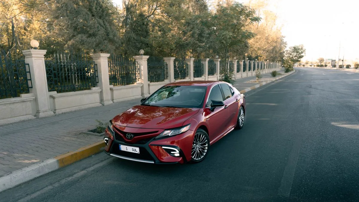 Illustrative red sedan parked on a city street
