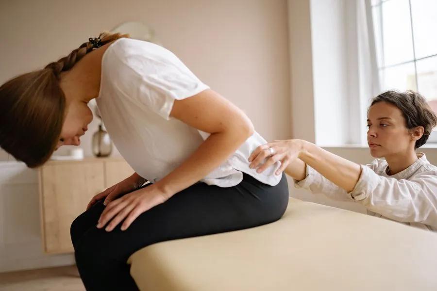Patient stretching her lower back during a guided mobility and posture session in a clinic