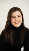Priya S., a woman in a black turtleneck, laughing