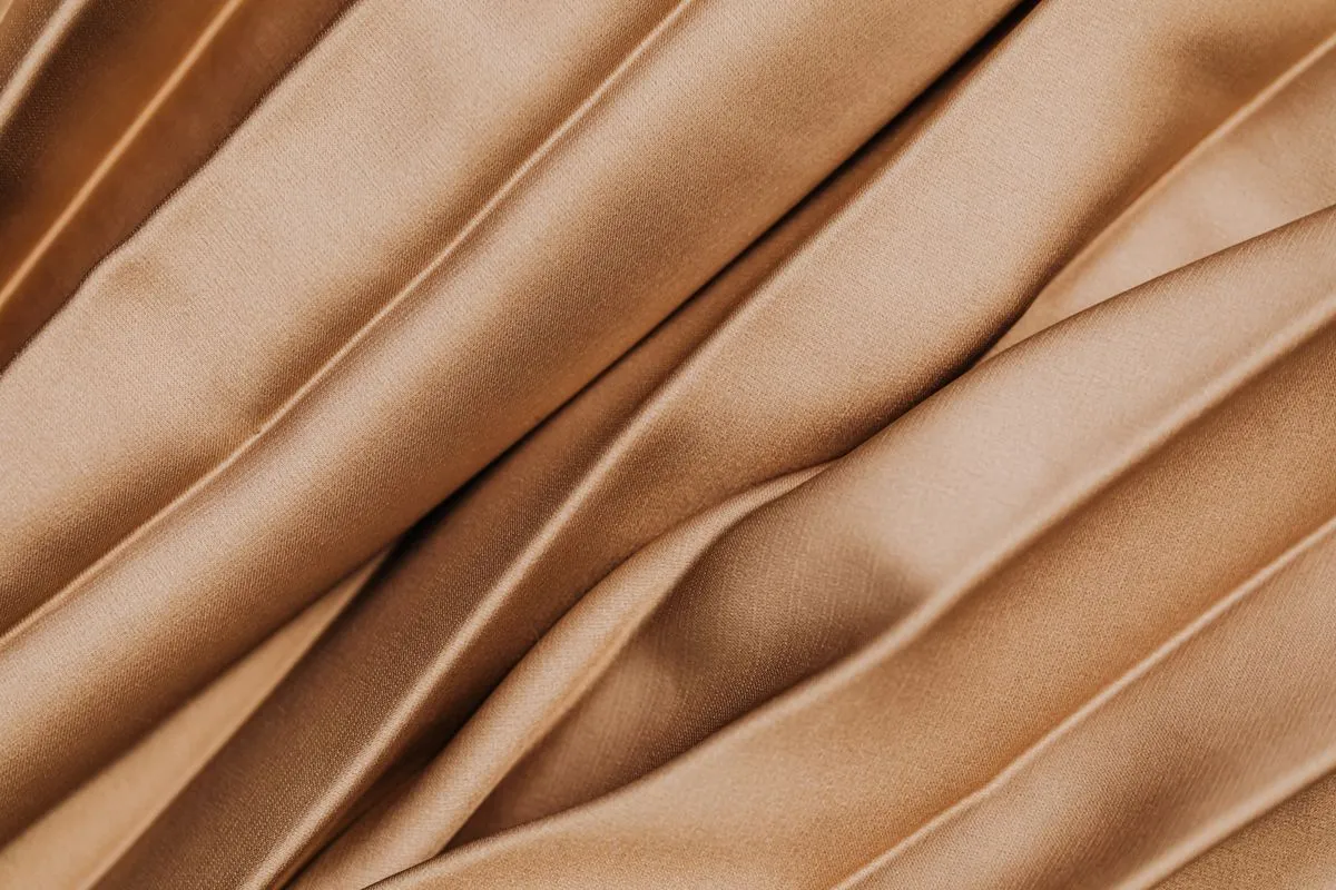 Beige pleated mulberry silk catching a soft sheen across its folds.