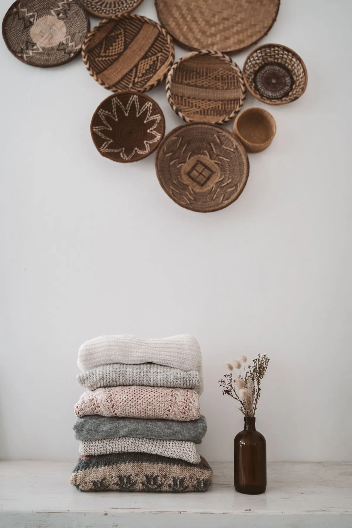 A lofty folded merino weekend knit beside woven storage baskets.