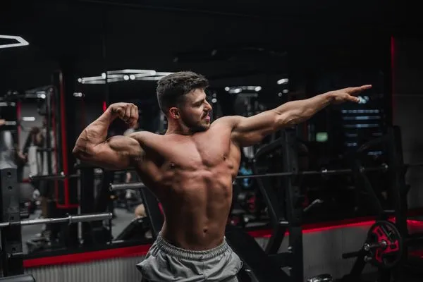 Marcus Reed, Founder & Head Coach, confident muscular coach in a dark gym with red accent lighting