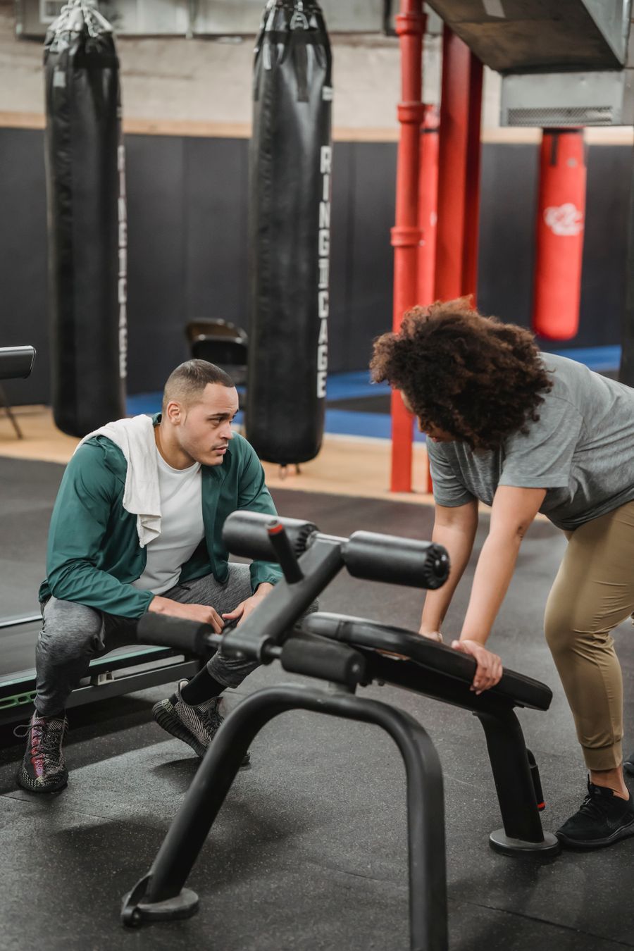 Personal trainer guiding a client through a back-extension bench exercise during a one-on-one gym session