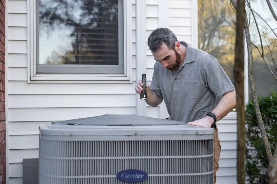 Technician inspecting and repairing an outdoor air conditioner condenser unit