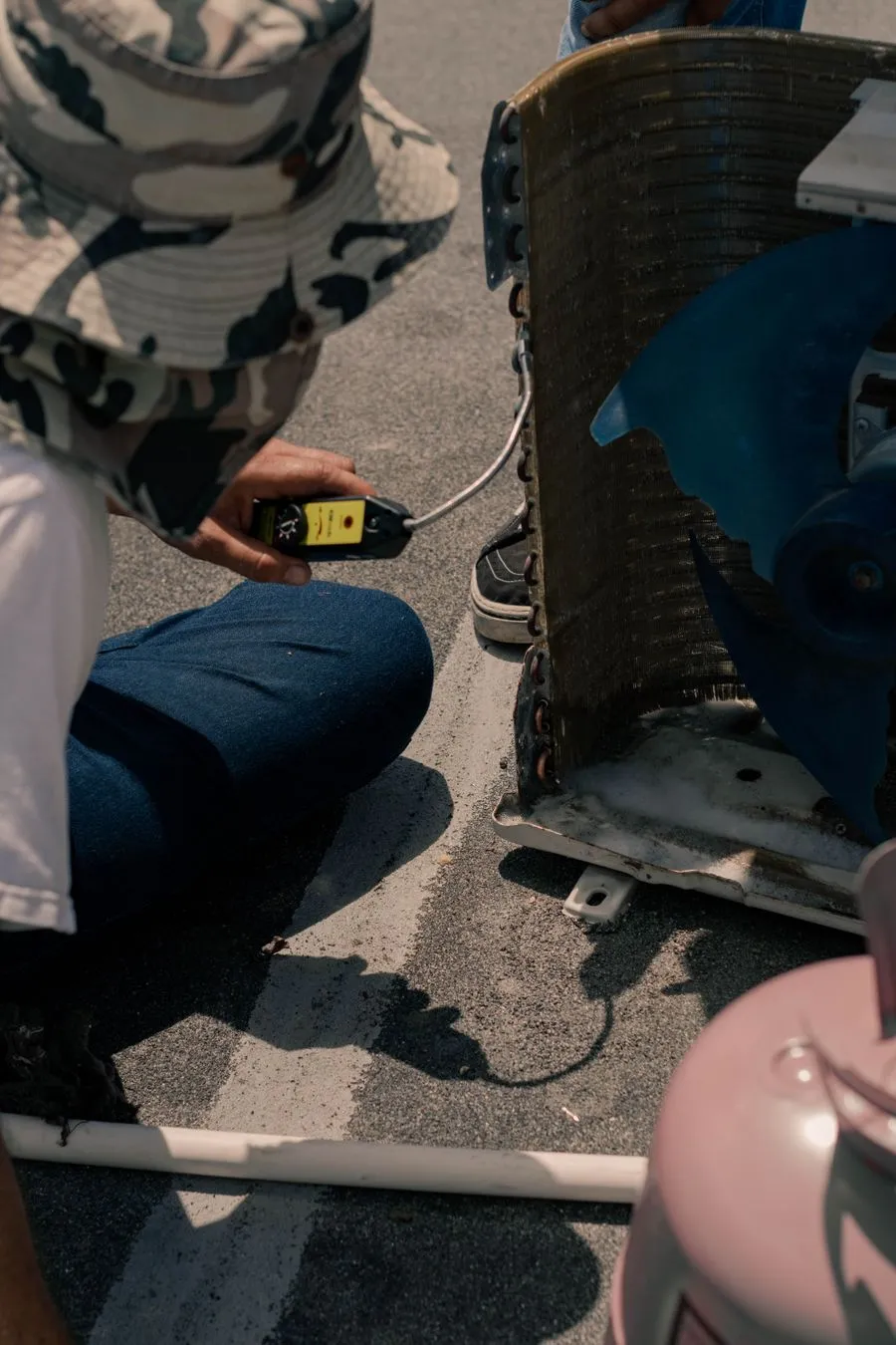 HVAC technician testing an air conditioning unit with a multimeter during a tune-up